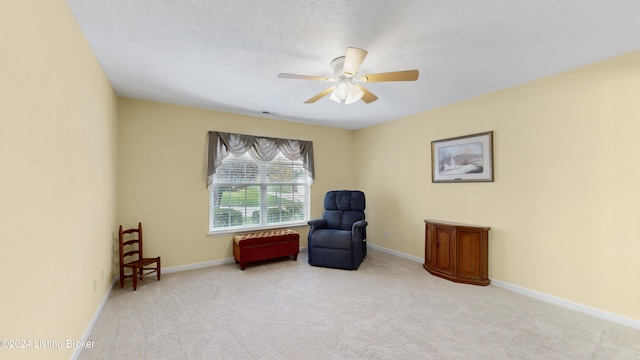 living area with a textured ceiling, ceiling fan, and light carpet