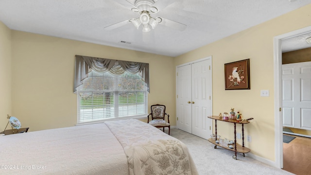 carpeted bedroom with ceiling fan, a closet, and a textured ceiling