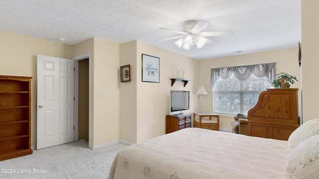 bedroom featuring a textured ceiling, light colored carpet, and ceiling fan