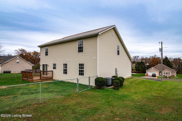 back of house featuring central AC unit, a lawn, and a wooden deck