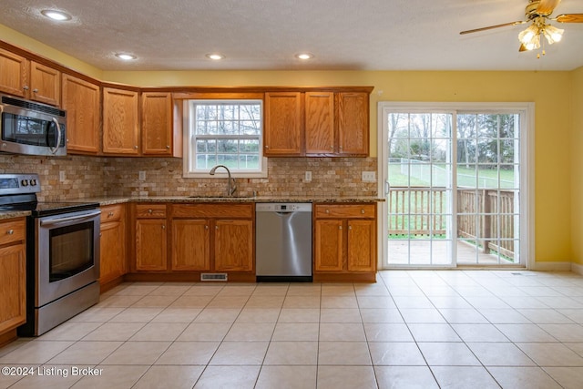 kitchen featuring light stone countertops, sink, ceiling fan, tasteful backsplash, and appliances with stainless steel finishes