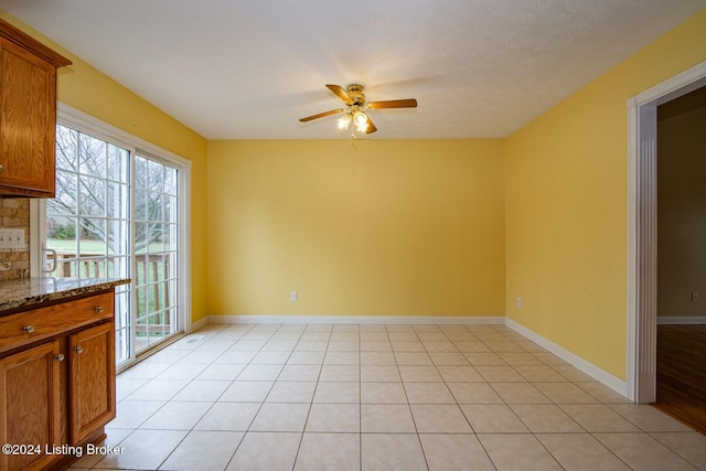 interior space featuring ceiling fan, light tile patterned floors, and a textured ceiling