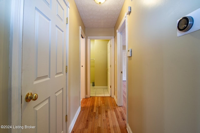 corridor featuring a textured ceiling and light wood-type flooring