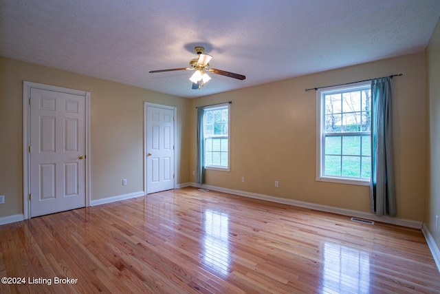 unfurnished bedroom featuring ceiling fan, light hardwood / wood-style floors, and a textured ceiling