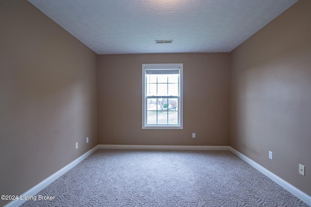 spare room with a textured ceiling and light colored carpet