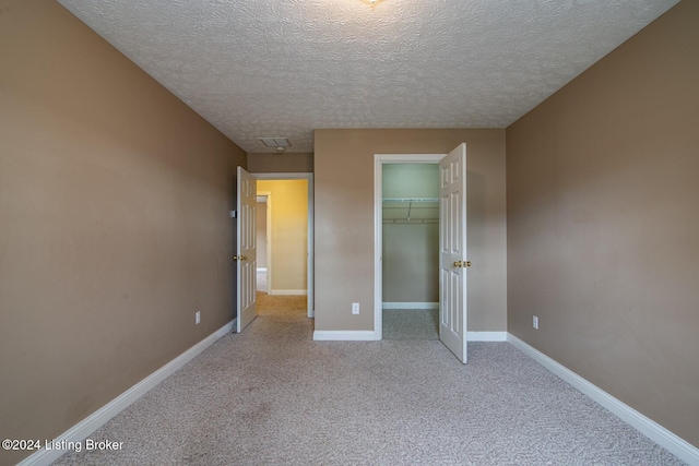 unfurnished bedroom featuring a textured ceiling, light colored carpet, and a closet