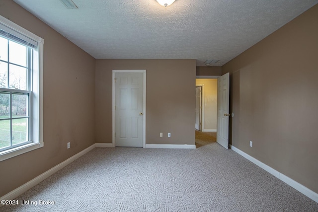 unfurnished bedroom featuring light carpet and a textured ceiling