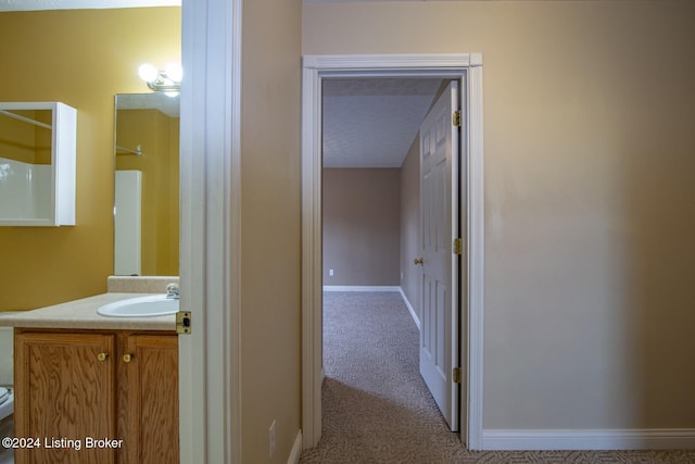 hall featuring light carpet, sink, and a textured ceiling