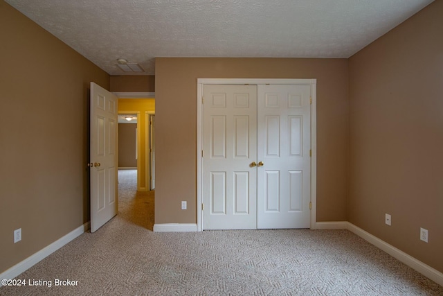 unfurnished bedroom featuring light carpet, a closet, and a textured ceiling