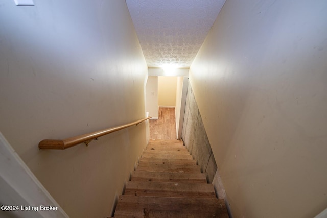 stairway featuring wood-type flooring and a textured ceiling