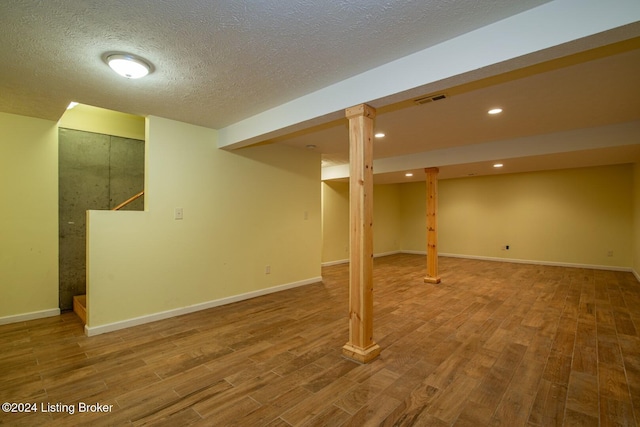 basement with hardwood / wood-style floors and a textured ceiling