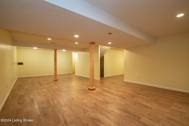 basement featuring a textured ceiling and hardwood / wood-style flooring