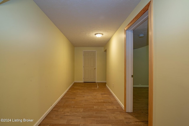 corridor featuring a textured ceiling and light wood-type flooring