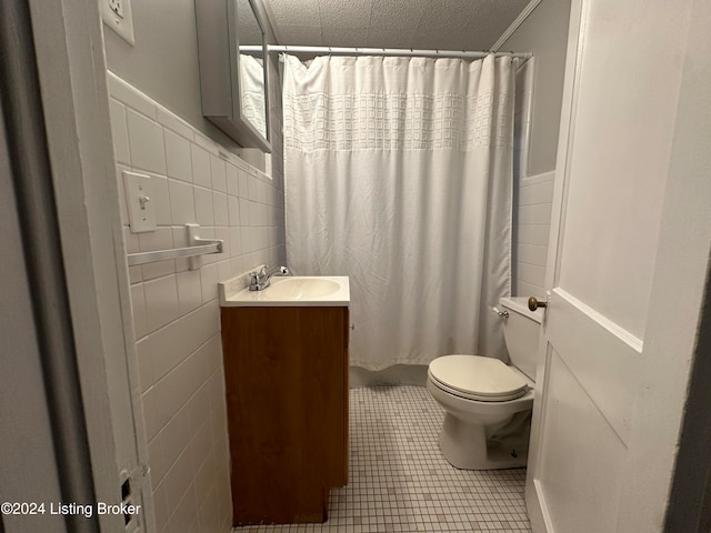 bathroom with tile patterned floors, vanity, a textured ceiling, tile walls, and toilet