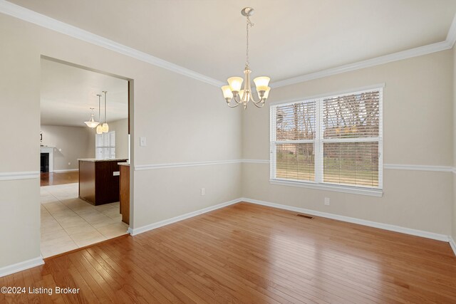 unfurnished room featuring a chandelier, light hardwood / wood-style flooring, and ornamental molding