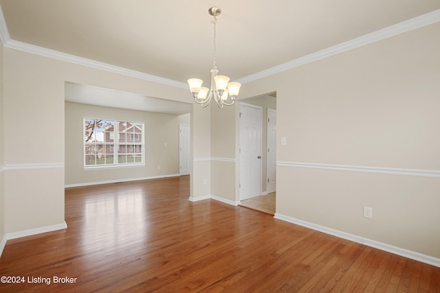 unfurnished room featuring a notable chandelier, wood-type flooring, and ornamental molding