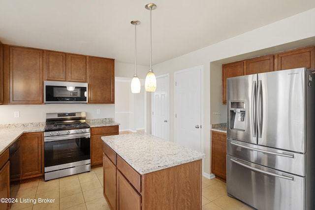 kitchen with light stone countertops, stainless steel appliances, pendant lighting, light tile patterned floors, and a center island