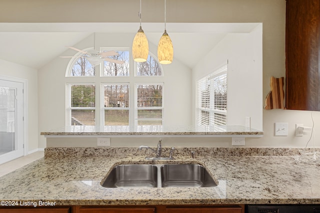 kitchen featuring light stone countertops, vaulted ceiling, ceiling fan, sink, and decorative light fixtures