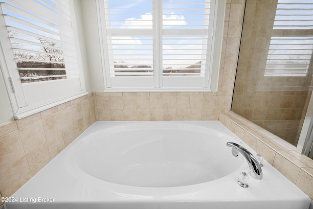 bathroom with a tub to relax in and a healthy amount of sunlight