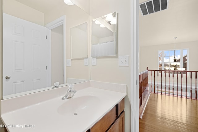 bathroom featuring hardwood / wood-style floors, vanity, and a chandelier