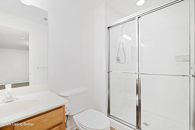 bathroom featuring a shower with door, vanity, and toilet