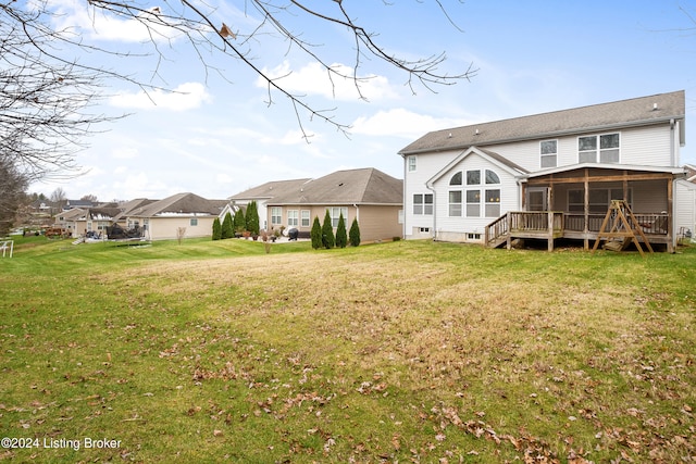 rear view of house featuring a yard, a sunroom, and a wooden deck