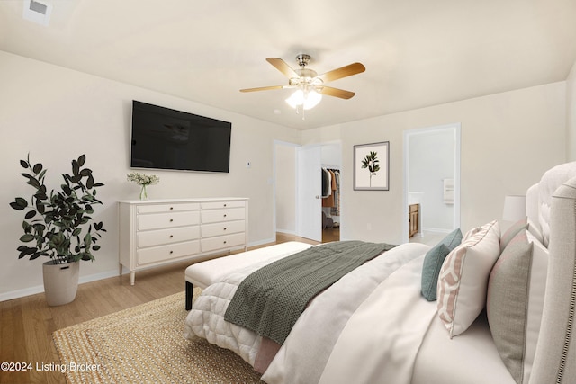 bedroom with ensuite bathroom, light hardwood / wood-style flooring, and ceiling fan