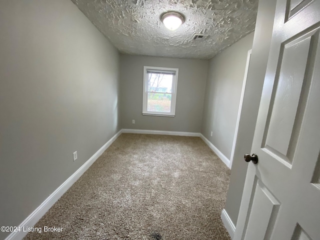 carpeted empty room with a textured ceiling