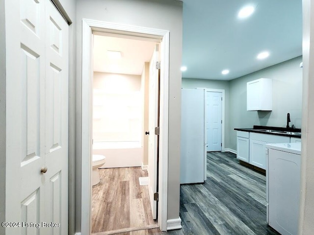 kitchen with dark hardwood / wood-style floors, white cabinetry, sink, and washer / clothes dryer