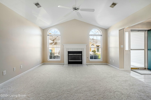 unfurnished living room featuring a healthy amount of sunlight, lofted ceiling, light carpet, and a tile fireplace