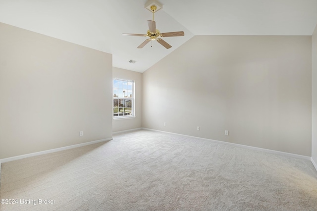 spare room with light carpet, vaulted ceiling, and ceiling fan