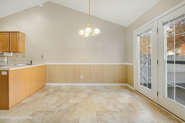 kitchen featuring sink, high vaulted ceiling, a chandelier, decorative light fixtures, and wooden walls