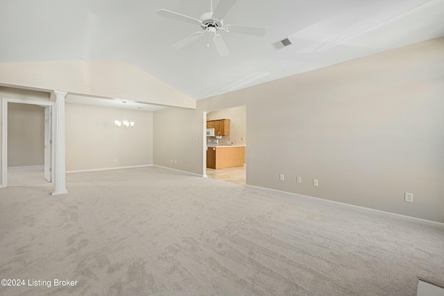 spare room featuring ceiling fan with notable chandelier, light colored carpet, and vaulted ceiling