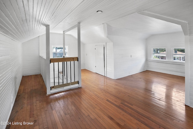 bonus room with wood-type flooring, lofted ceiling, and brick wall