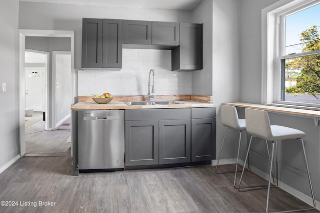 kitchen with backsplash, stainless steel dishwasher, dark wood-type flooring, sink, and gray cabinets