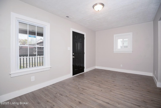 unfurnished room with dark wood-type flooring and a textured ceiling