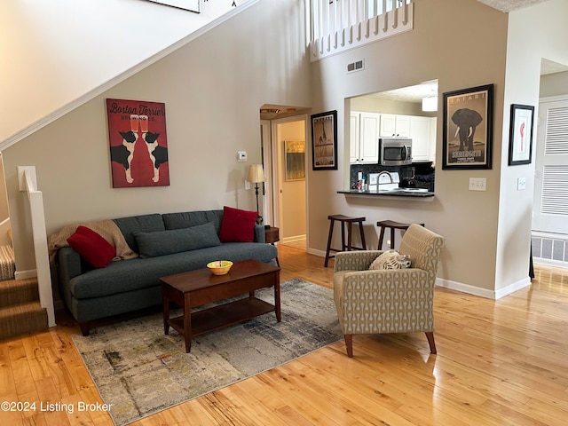 living room with a towering ceiling and light wood-type flooring