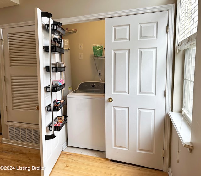 clothes washing area with ornamental molding, light hardwood / wood-style floors, and washer / dryer