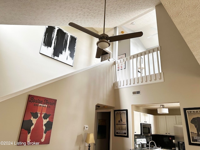 interior space with a textured ceiling, ceiling fan, sink, and high vaulted ceiling