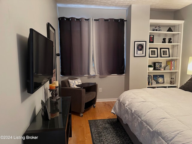 bedroom with light hardwood / wood-style floors and a textured ceiling