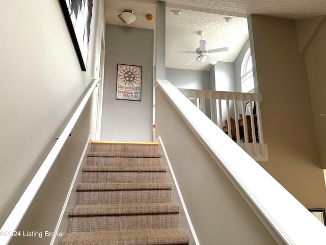 staircase featuring ceiling fan and a textured ceiling