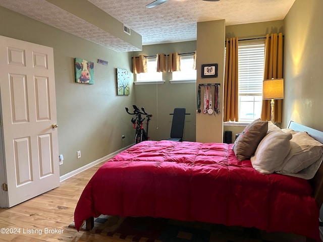 bedroom with multiple windows, a textured ceiling, and hardwood / wood-style flooring