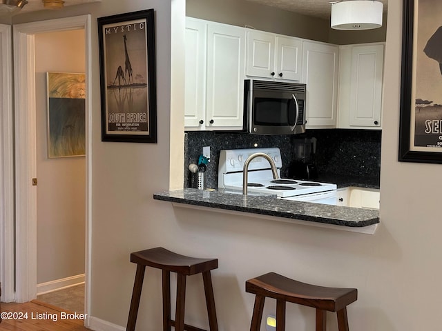 kitchen with tasteful backsplash, electric range, white cabinets, and dark hardwood / wood-style floors