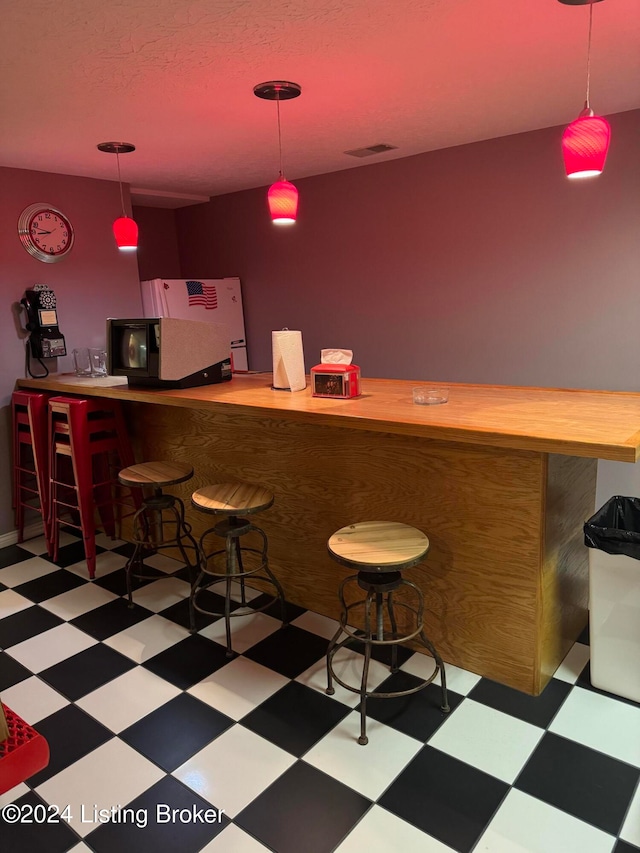 bar with pendant lighting and fridge