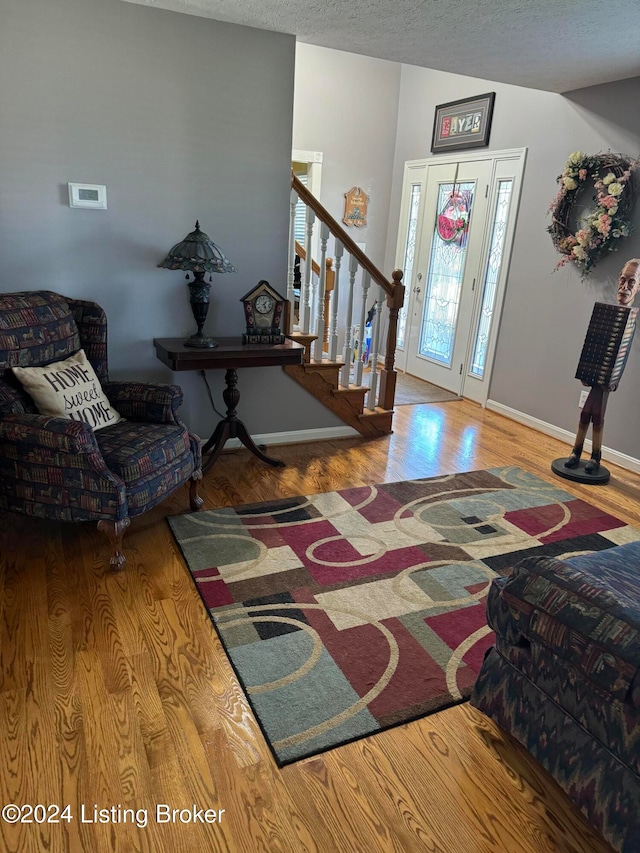 foyer entrance with lofted ceiling, hardwood / wood-style floors, and a textured ceiling