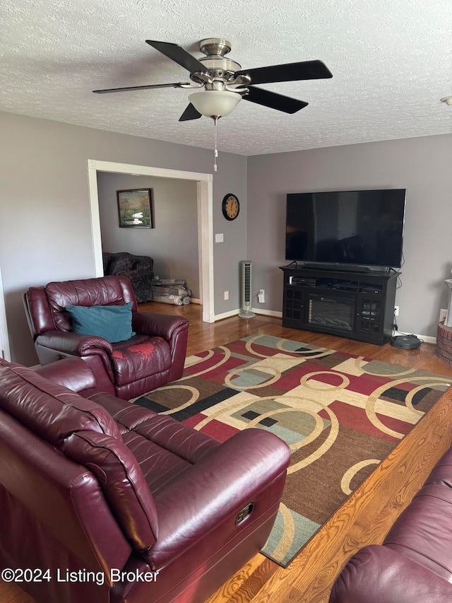 living room with hardwood / wood-style floors, a textured ceiling, and ceiling fan