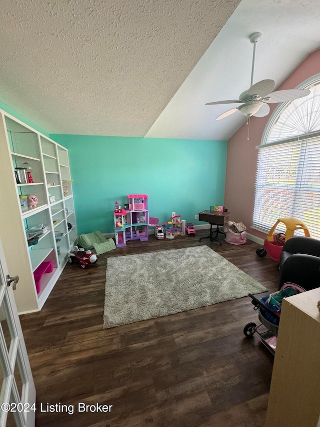 recreation room featuring a textured ceiling, dark hardwood / wood-style flooring, vaulted ceiling, and ceiling fan