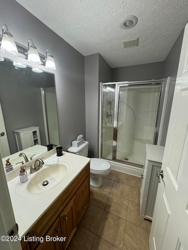 bathroom featuring tile patterned flooring, an enclosed shower, a textured ceiling, toilet, and vanity