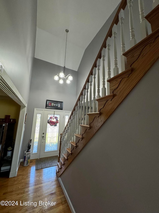 entrance foyer featuring hardwood / wood-style floors, high vaulted ceiling, and a chandelier