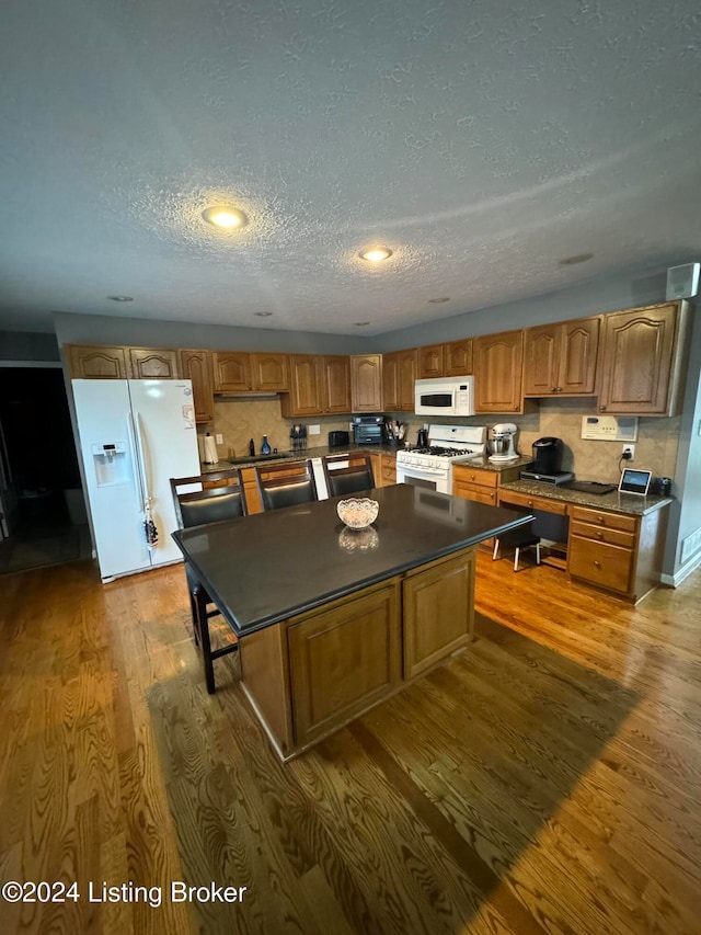 kitchen featuring a kitchen island, white appliances, dark wood-type flooring, and tasteful backsplash